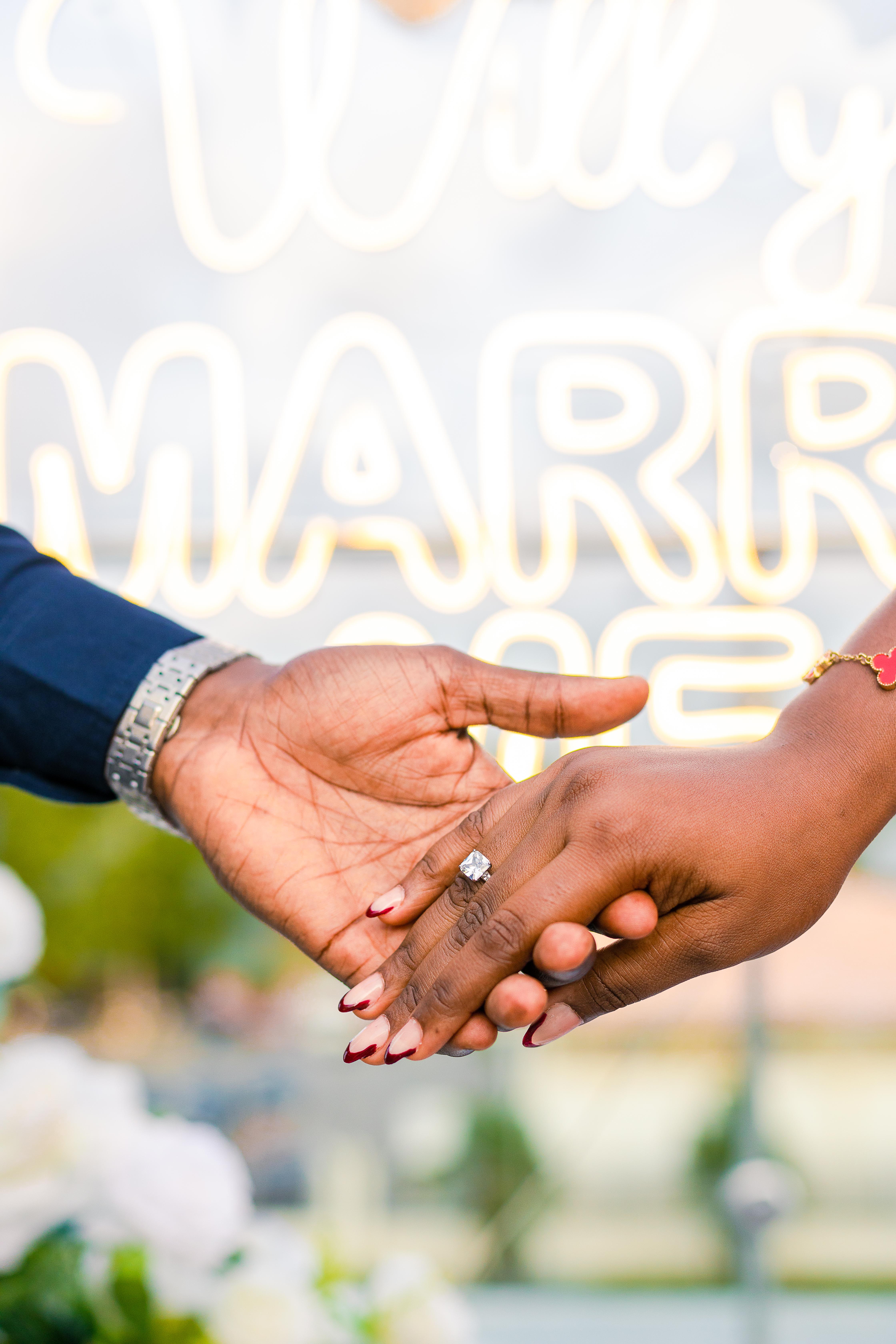 Close-up of Precious and Emmanuel holding hands with an engagement ring visible