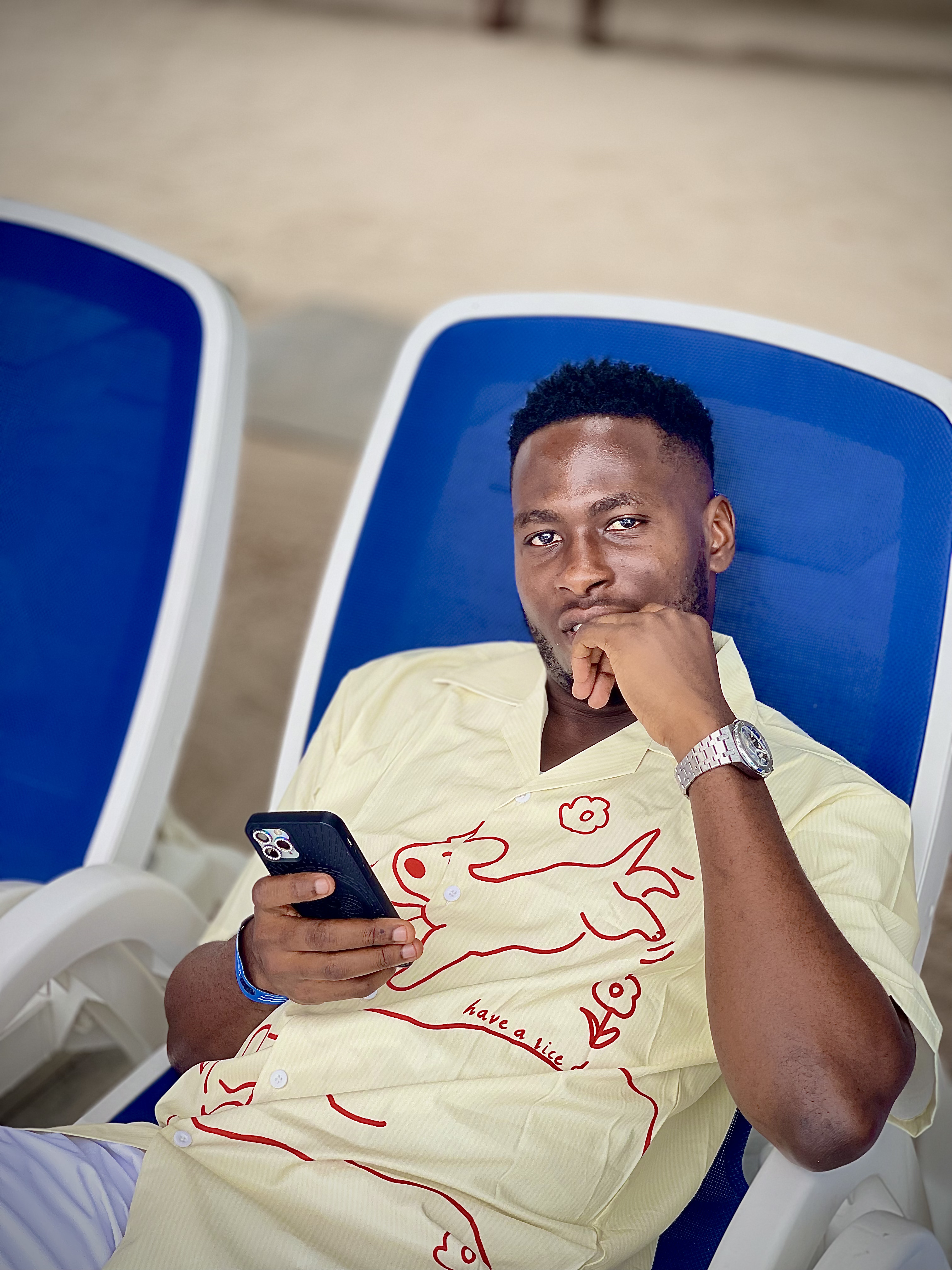 Emmanuel seated and holding his phone